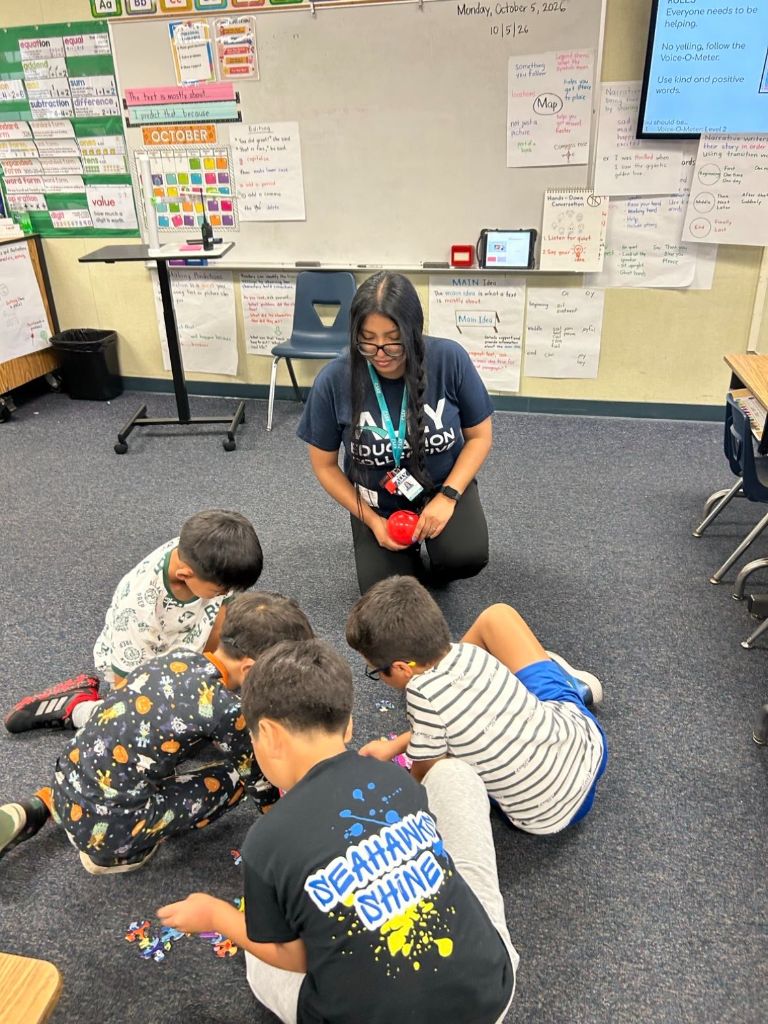Victoria Hernandez Noria working with students on the floor during an after-school expanded learning session at Fullerton School District